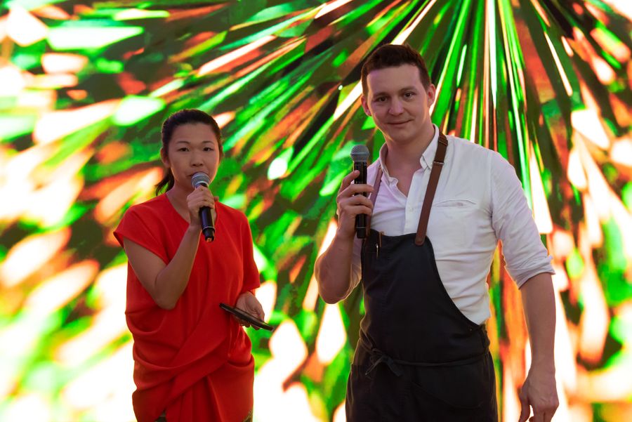 Tammie speaking on stage with a microphone beside a chef