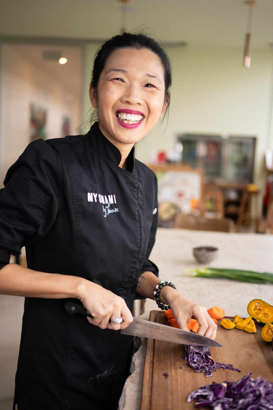Tammie in chef's whites, laughing as she slices vegetables