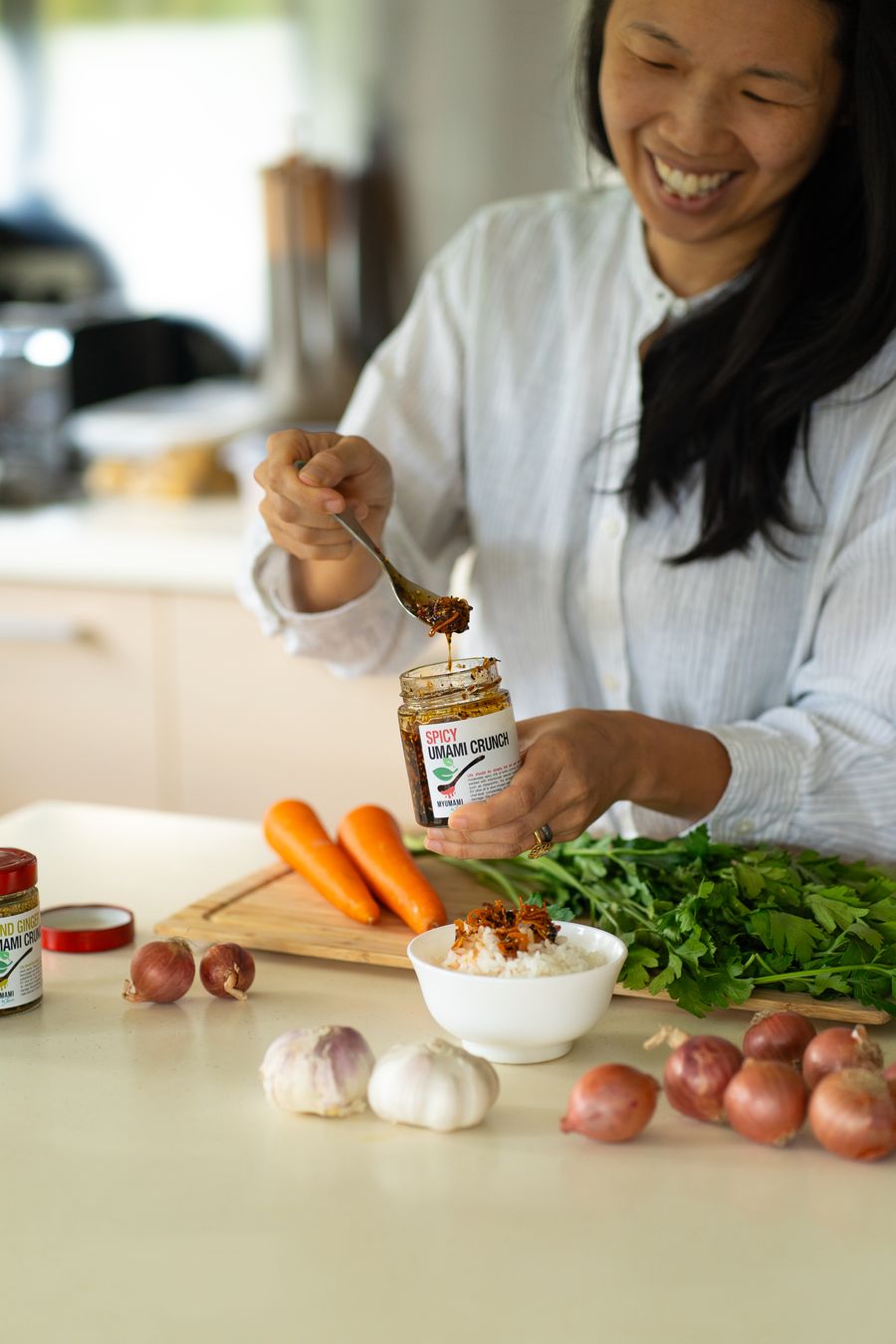 Tammie spooning a savoury paste from a jar, fresh carrots and greens on the board
