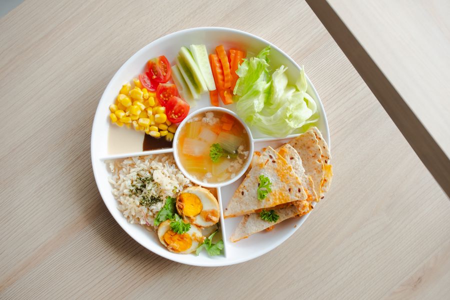 A Kensington school lunch plate with vegetables, grains and soup