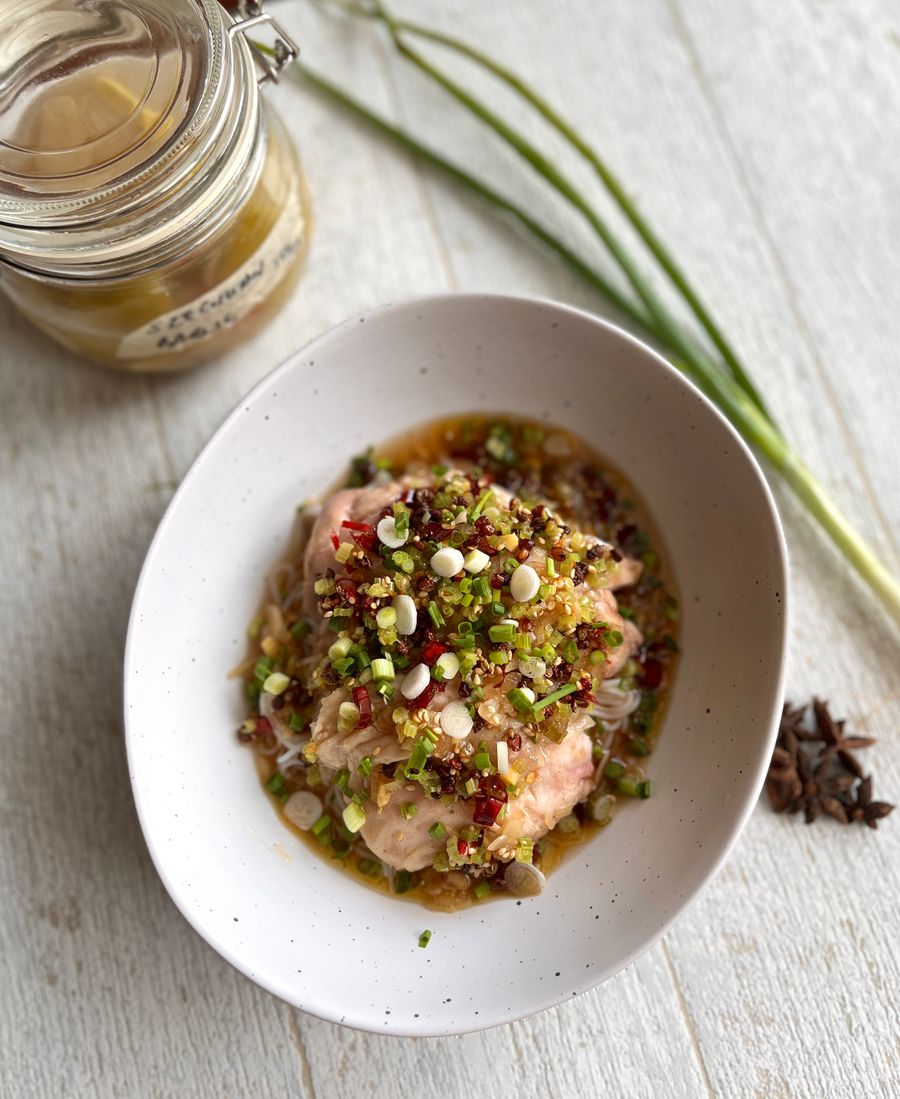 A bowl of fermented chicken topped with herbs and seeds
