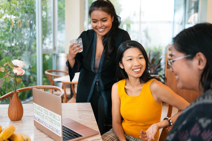 Tammie laughing at a table with two women, a laptop open beside them