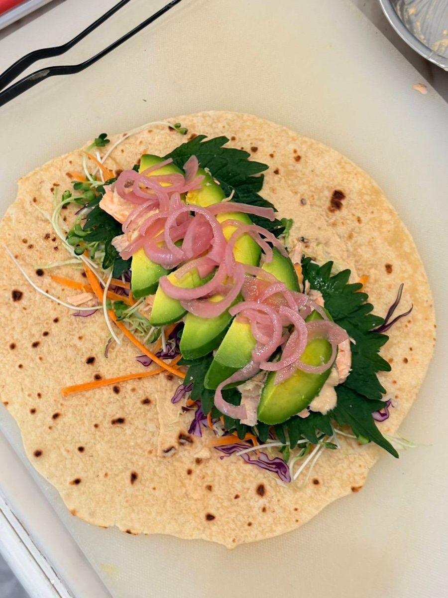 A Mother May I umami wrap, open, with avocado, pickled red onion, greens and shredded vegetables