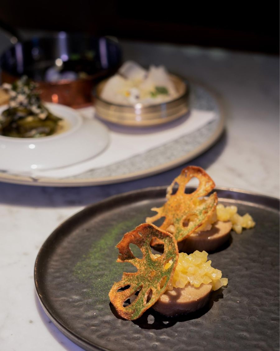 A plated dish with crisp lotus root on a dark plate
